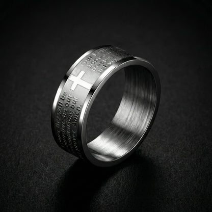 Silver ring with engraved text and cross design on a dark background